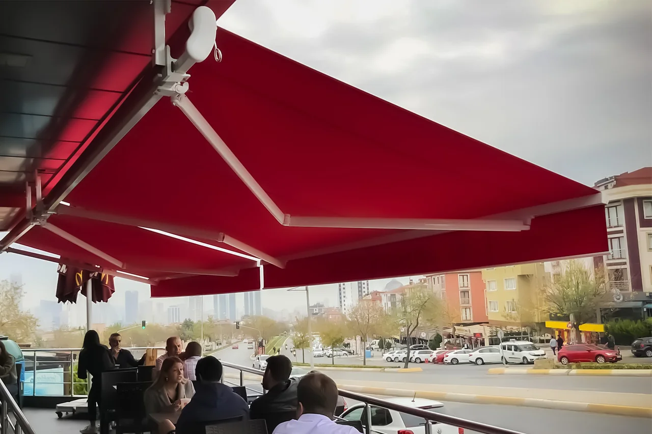 Kafe oturma alanı üzerinde açık bordo mafsallı tente